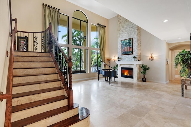 stairs featuring a fireplace and a high ceiling