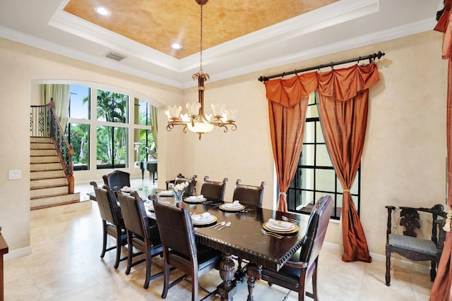 dining space with ornamental molding, light tile patterned floors, an inviting chandelier, and a tray ceiling