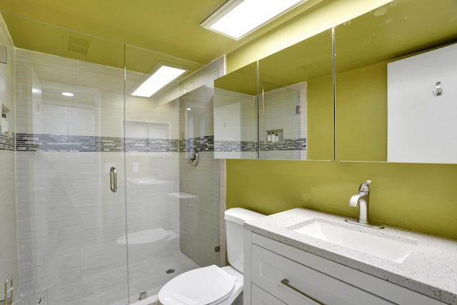 bathroom featuring vanity, toilet, and a shower with shower door