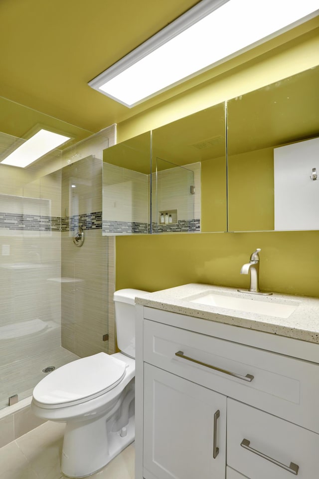 bathroom with vanity, a tile shower, and toilet