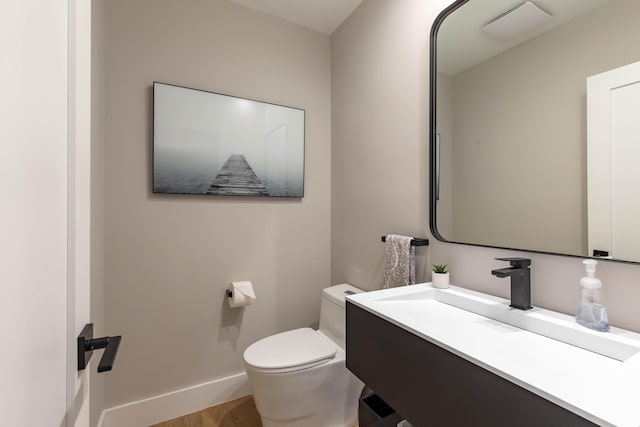 bathroom with hardwood / wood-style flooring, toilet, and vanity