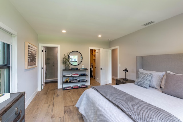 bedroom with light hardwood / wood-style floors, a closet, connected bathroom, and a walk in closet