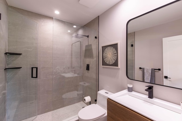 bathroom featuring a shower with shower door, toilet, and vanity