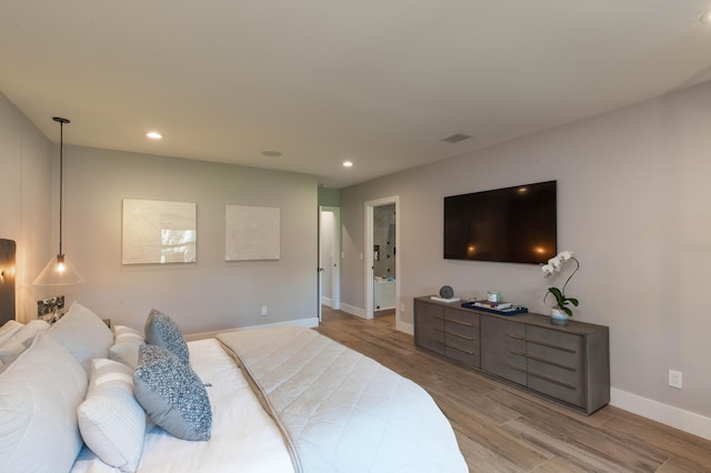 bedroom with light hardwood / wood-style flooring and ensuite bath