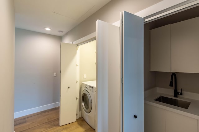 washroom featuring sink, light hardwood / wood-style flooring, and washer / dryer