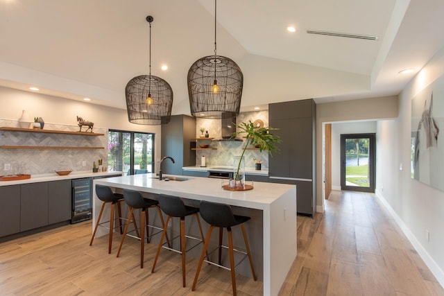 kitchen with sink, an island with sink, backsplash, and beverage cooler