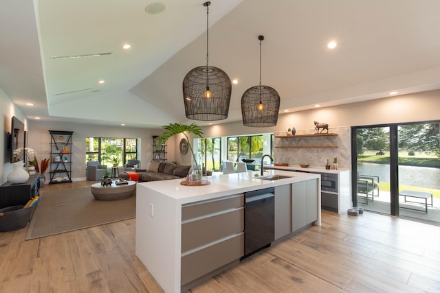 kitchen with tasteful backsplash, sink, dishwasher, a center island with sink, and light hardwood / wood-style flooring