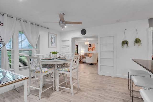 dining area featuring ceiling fan with notable chandelier, built in features, and light wood-type flooring