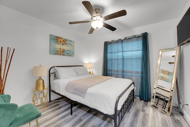 bedroom with a textured ceiling, wood-type flooring, and ceiling fan