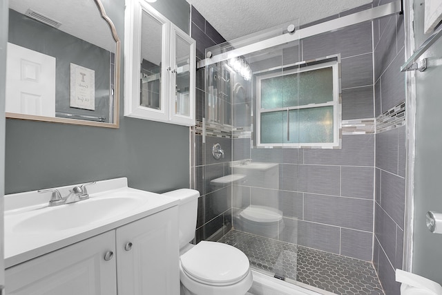 bathroom featuring an enclosed shower, vanity, a textured ceiling, and toilet