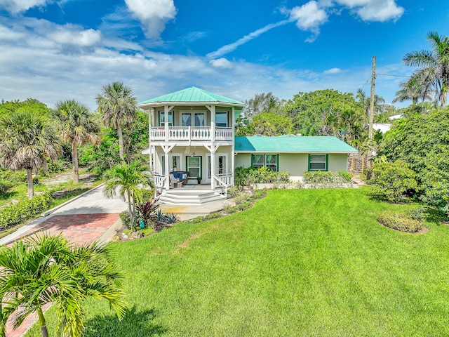 back of property featuring a balcony, covered porch, and a lawn