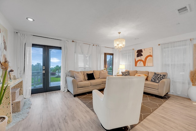 living room featuring wood-type flooring, an inviting chandelier, and french doors