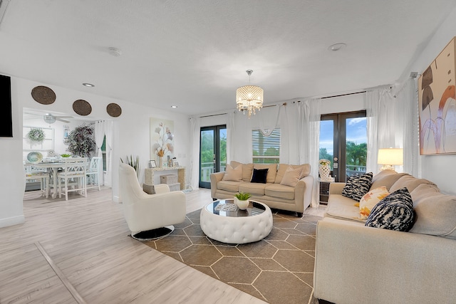 living room with an inviting chandelier, a healthy amount of sunlight, wood-type flooring, and french doors