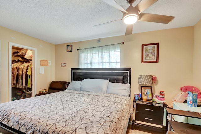 bedroom with ceiling fan, a textured ceiling, a closet, and a walk in closet