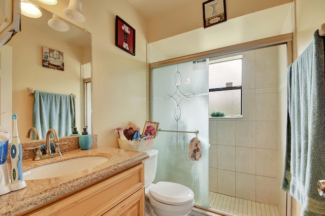 bathroom with vanity, a shower with door, and toilet