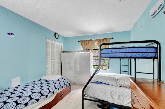 bedroom featuring a closet, light tile patterned floors, and a textured ceiling