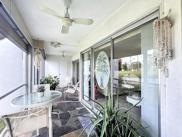 sunroom featuring ceiling fan and a water view