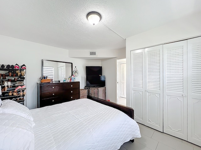 bedroom with light tile patterned floors, a textured ceiling, and a closet