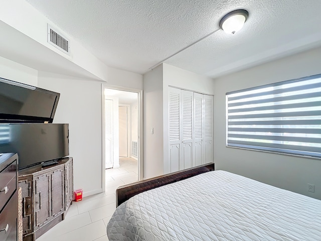 bedroom with light tile patterned floors and a textured ceiling