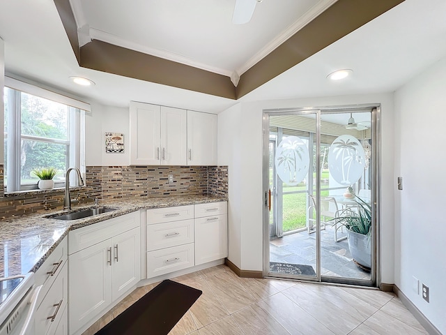 kitchen with white cabinetry, sink, light stone countertops, backsplash, and range