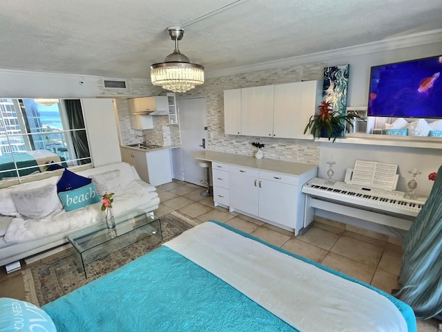 kitchen with a notable chandelier, white cabinetry, tasteful backsplash, ornamental molding, and light tile patterned floors