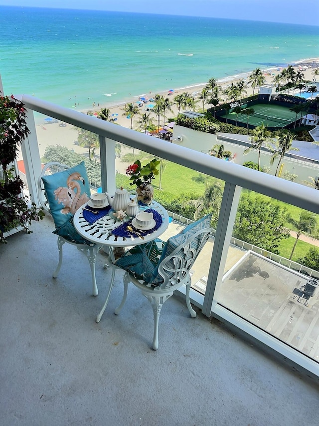 balcony featuring a view of the beach and a water view