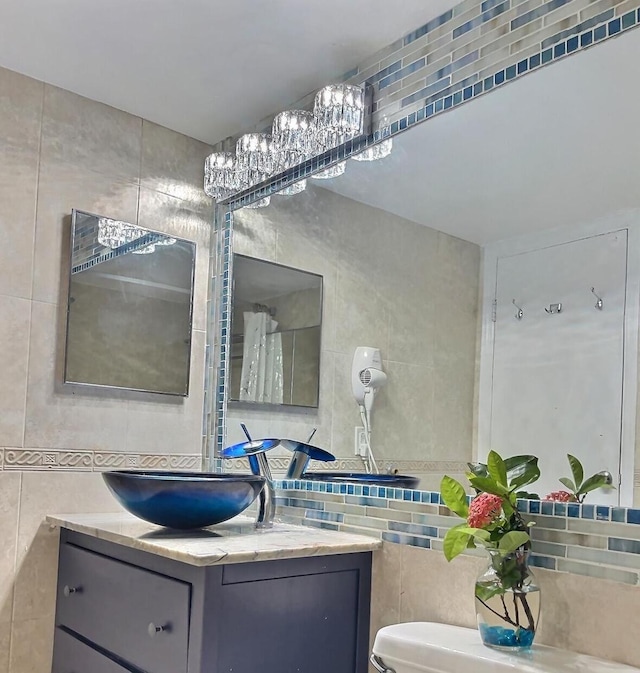 bathroom featuring vanity, backsplash, tile walls, and toilet