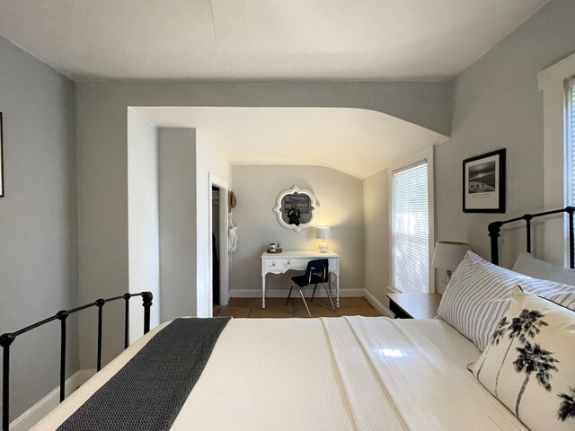 tiled bedroom featuring arched walkways, ceiling fan, lofted ceiling, and baseboards