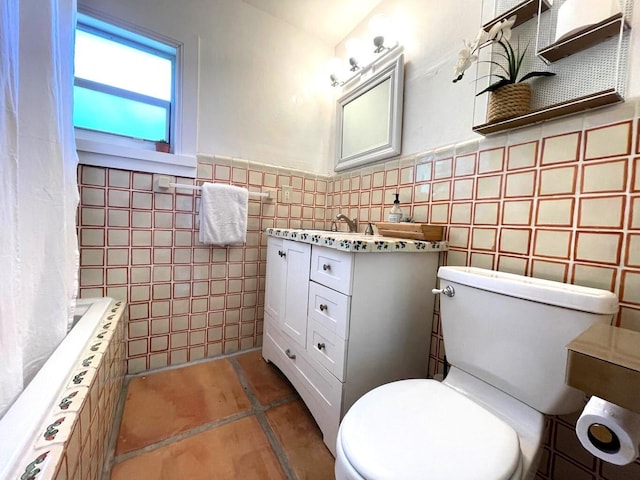 bathroom featuring wainscoting, vanity, toilet, and tile walls