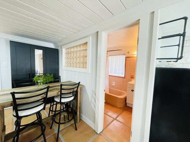 kitchen featuring light stone counters, tasteful backsplash, freestanding refrigerator, white cabinets, and a sink