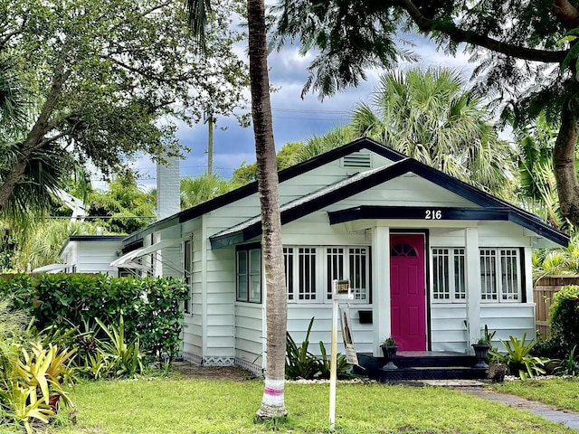 bungalow featuring entry steps, fence, a chimney, and a front yard