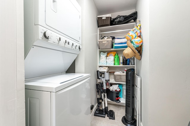 laundry area with stacked washer / dryer and tile patterned flooring