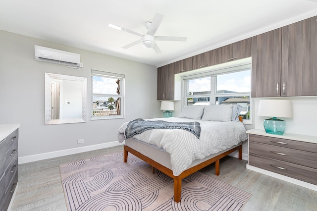 bedroom featuring a wall mounted AC, light wood-type flooring, and ceiling fan