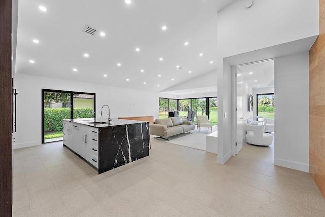 kitchen with sink, a center island with sink, high vaulted ceiling, a healthy amount of sunlight, and white cabinets