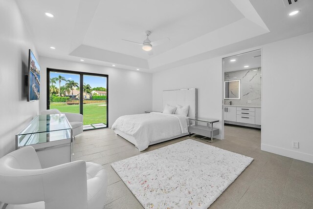 bedroom featuring ceiling fan, access to exterior, ensuite bathroom, and a tray ceiling