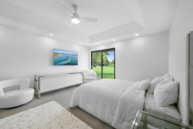 bedroom with ceiling fan, a raised ceiling, and access to exterior