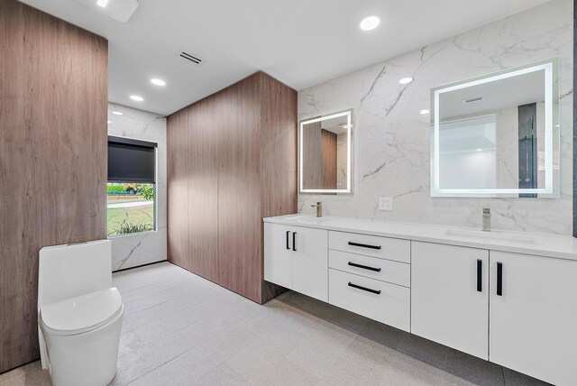 bathroom with tile walls, double vanity, toilet, and tile patterned flooring