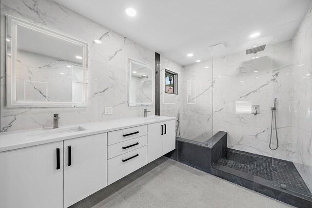 bathroom featuring double sink vanity, tile walls, tile patterned flooring, and a tile shower