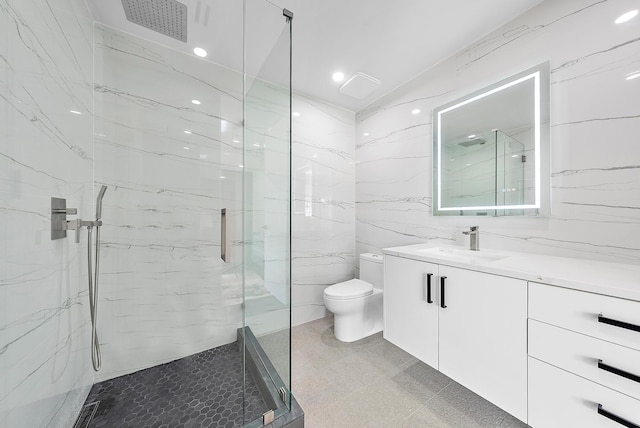 bathroom with tile walls, a shower with door, toilet, vanity, and tile patterned flooring