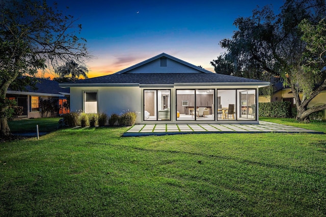 back house at dusk with a lawn