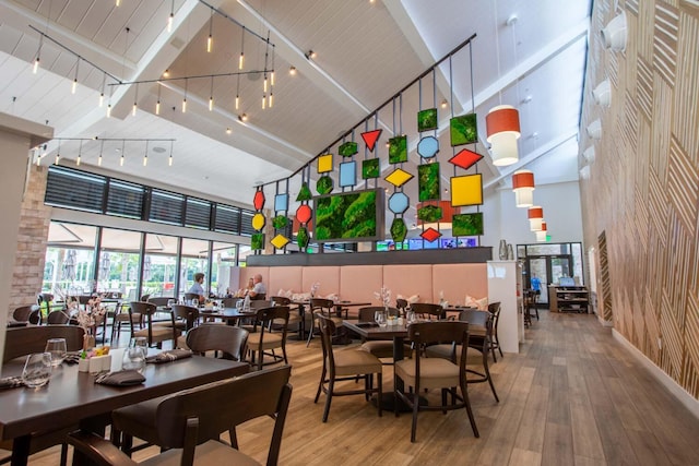 dining room with hardwood / wood-style flooring, rail lighting, and high vaulted ceiling