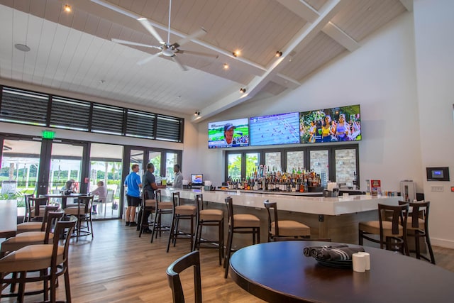 interior space with ceiling fan, high vaulted ceiling, beam ceiling, and wood-type flooring