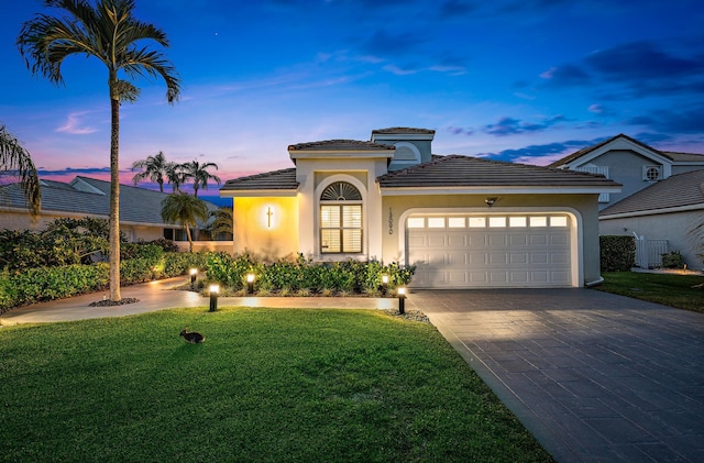 mediterranean / spanish home featuring a garage and a lawn