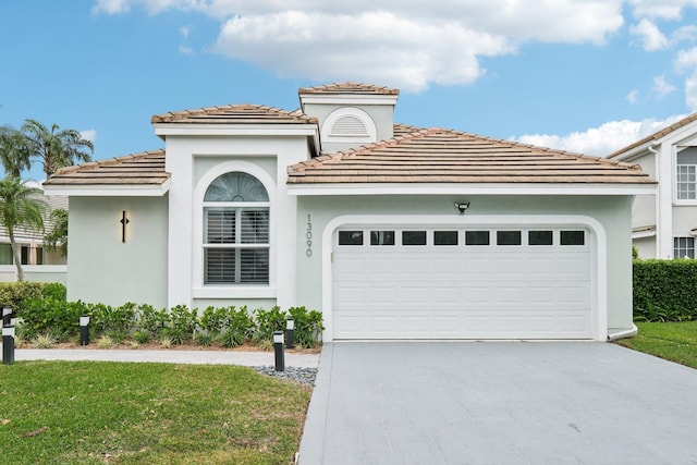 mediterranean / spanish house featuring a front yard and a garage