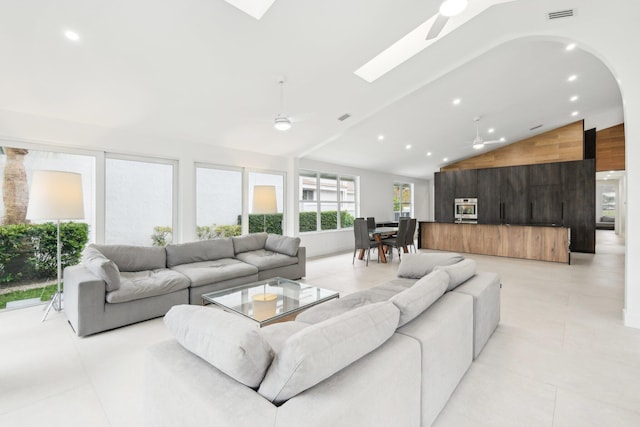 living room with ceiling fan and lofted ceiling with skylight