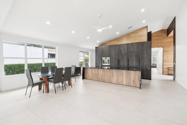 kitchen featuring vaulted ceiling, wood walls, ceiling fan, sink, and oven