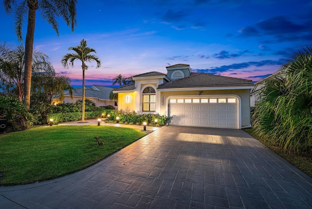 mediterranean / spanish-style home featuring a yard and a garage