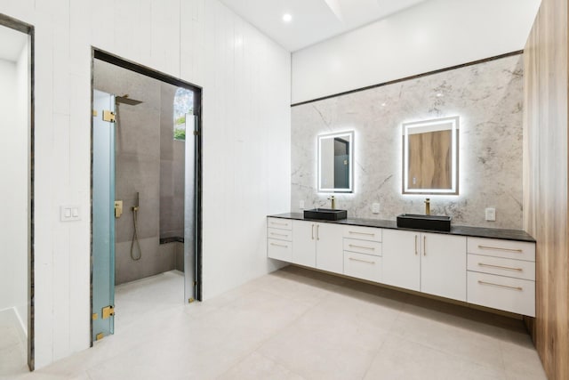 bathroom with a tile shower and vanity