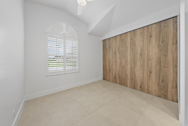 tiled empty room featuring ceiling fan and vaulted ceiling