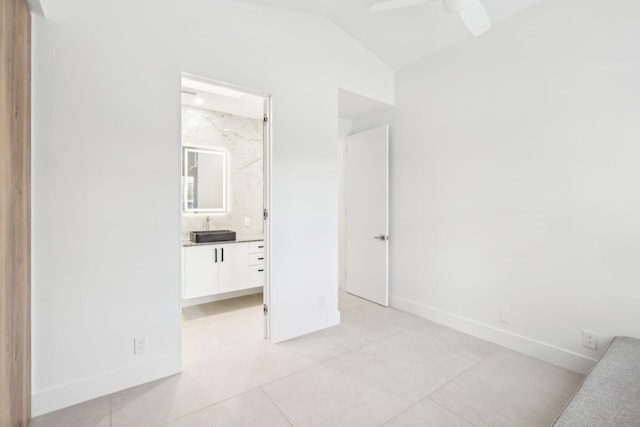 unfurnished bedroom featuring sink, vaulted ceiling, ceiling fan, light tile patterned floors, and ensuite bath